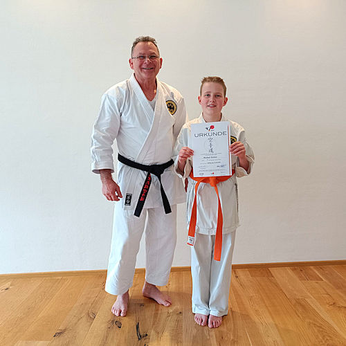 Karatetrainer Kuda mit seinem Sch&uuml;tzling, welcher die Pr&uuml;fung zum orangen Gurt abgelegt hatte